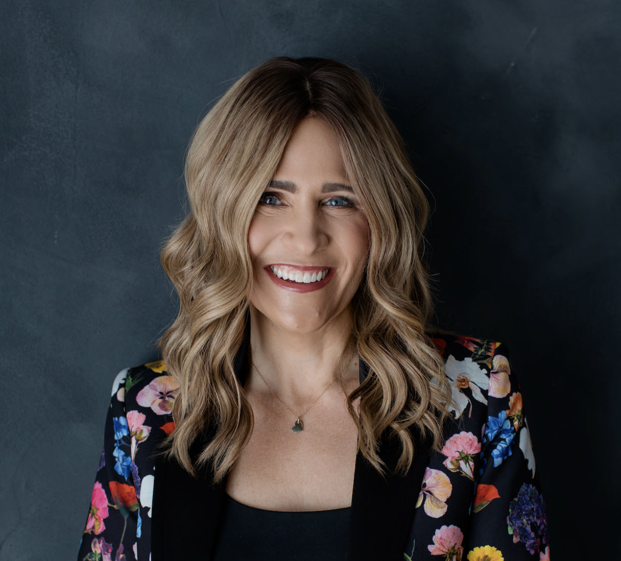 Portrait of Barbara Betts smiling against a dark teal studio backdrop